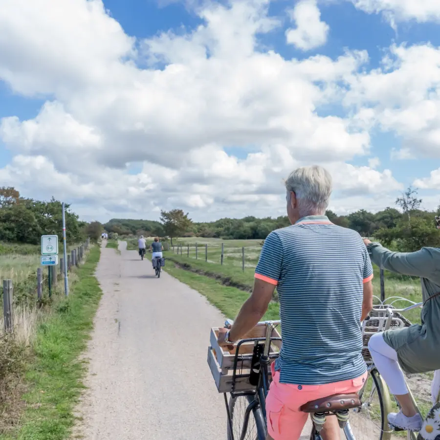 Echtpaar fietst door de duinen en wijst naar knooppunten renesse